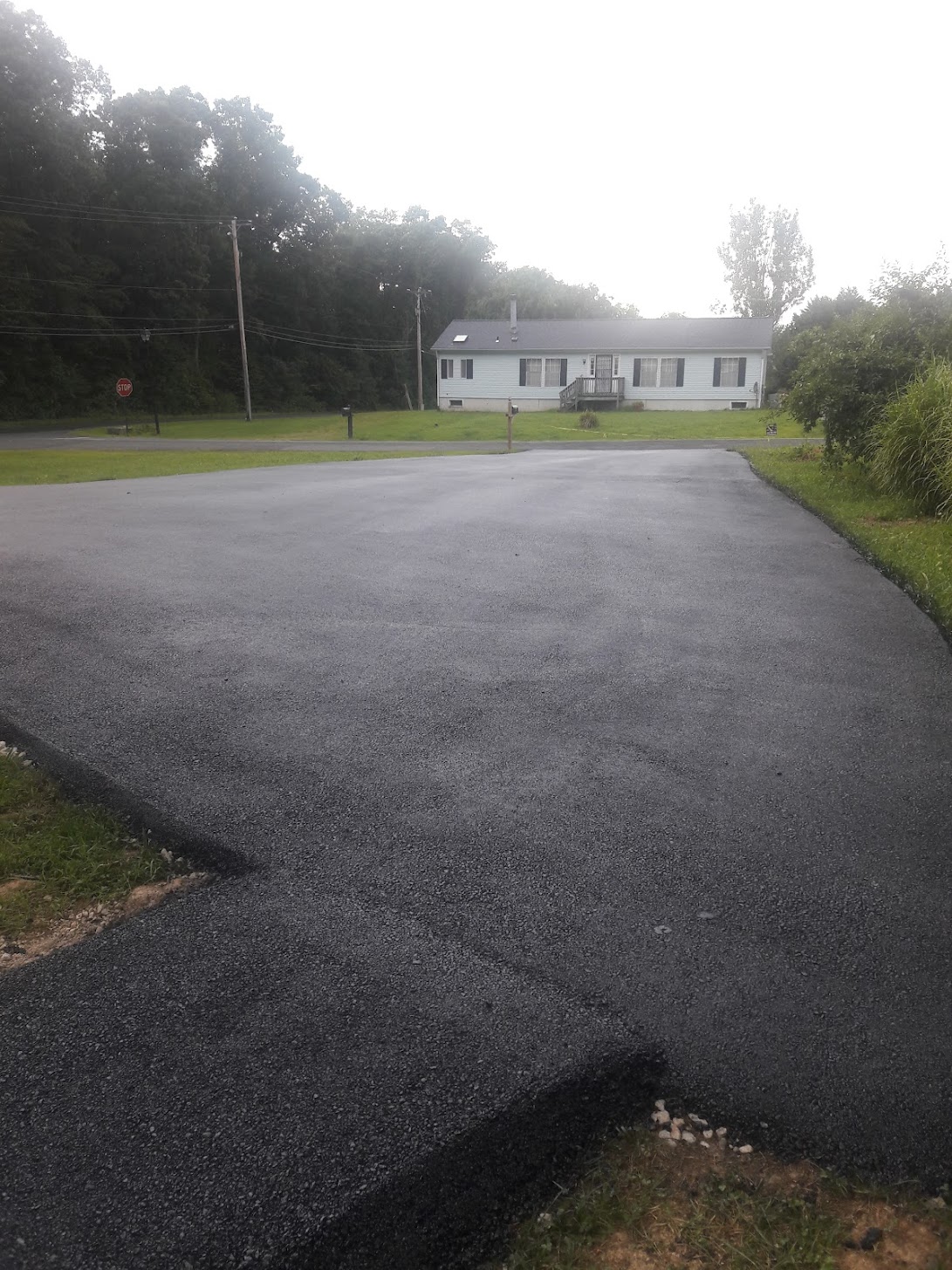 download-1 A paving machine spreads fresh asphalt on a road on a sunny day.